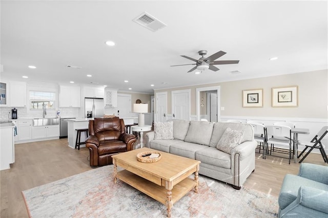 living room featuring light wood-type flooring, ceiling fan, and sink