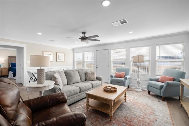 living room featuring hardwood / wood-style flooring, ceiling fan, and crown molding