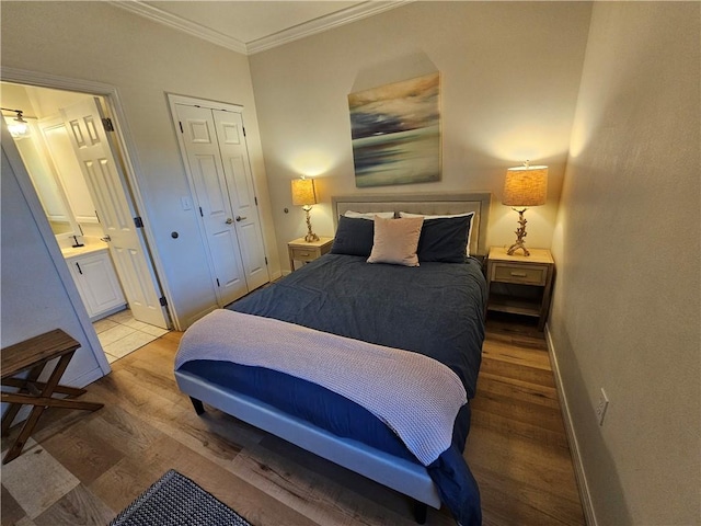 bedroom featuring hardwood / wood-style flooring, crown molding, ensuite bathroom, and a closet