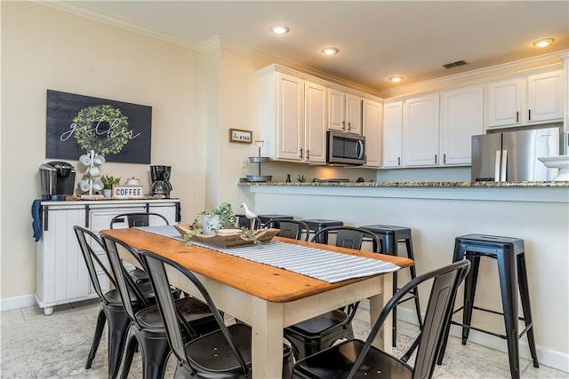 kitchen with crown molding, light tile patterned floors, kitchen peninsula, stainless steel appliances, and white cabinets