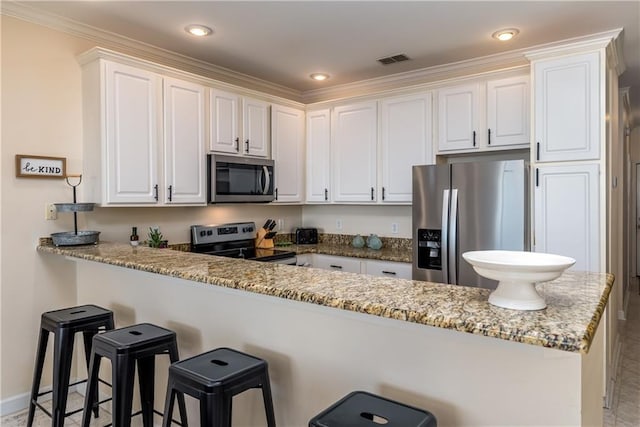 kitchen featuring a breakfast bar, kitchen peninsula, stainless steel appliances, light stone countertops, and white cabinets