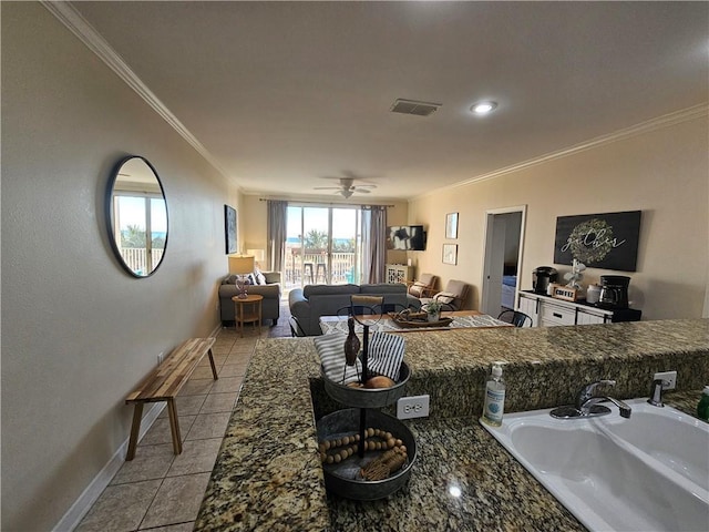 kitchen featuring sink, dark stone countertops, ornamental molding, light tile patterned floors, and ceiling fan