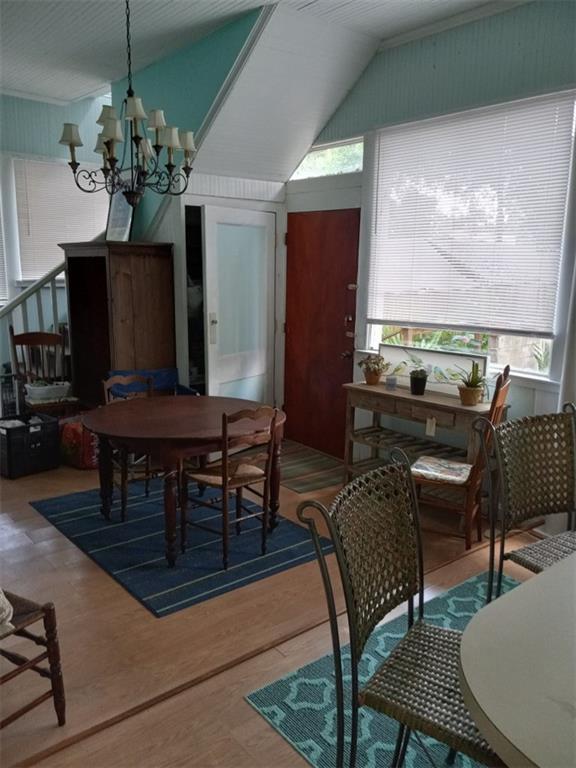 dining area with hardwood / wood-style floors, a chandelier, and vaulted ceiling