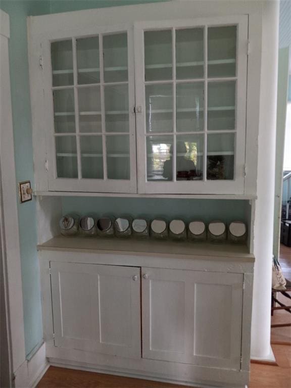 bar with white cabinetry and light hardwood / wood-style floors