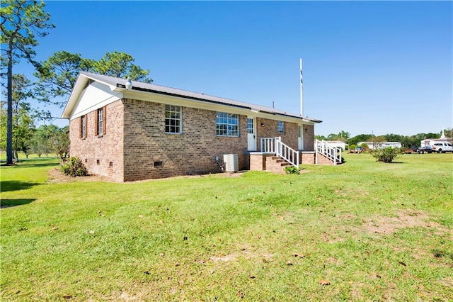 rear view of house featuring a lawn and central AC unit