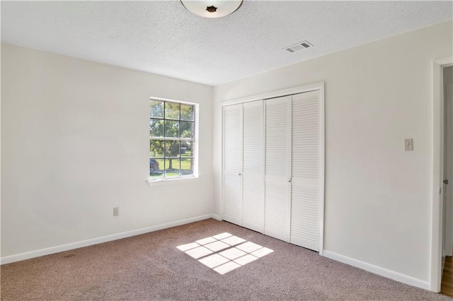 unfurnished bedroom featuring a closet, carpet flooring, and a textured ceiling