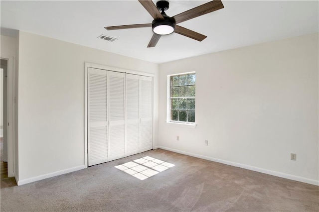 unfurnished bedroom featuring ceiling fan, light colored carpet, and a closet