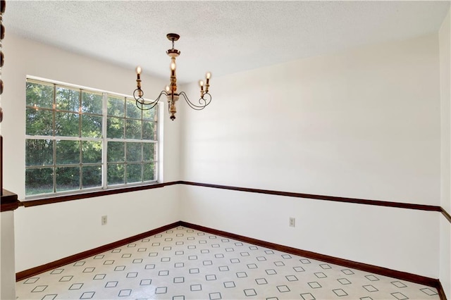 unfurnished room featuring a chandelier and a textured ceiling