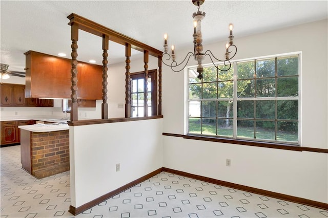 kitchen with hanging light fixtures, a chandelier, kitchen peninsula, and a wealth of natural light