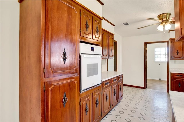 kitchen with ceiling fan, a textured ceiling, and oven