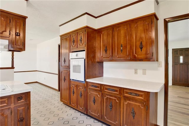 kitchen with light hardwood / wood-style floors, oven, and a textured ceiling