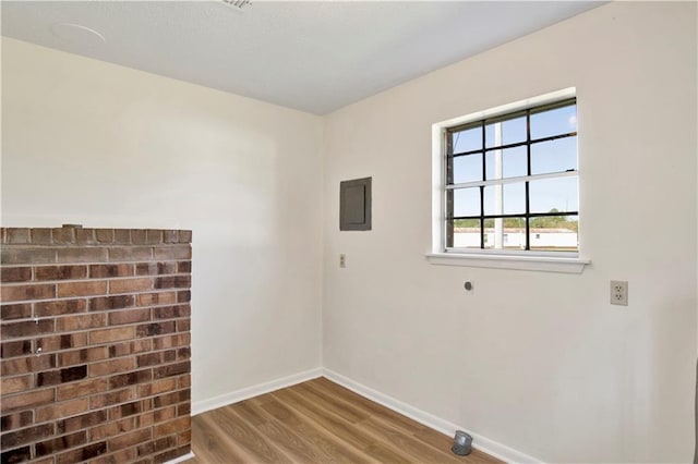 empty room with hardwood / wood-style flooring and electric panel