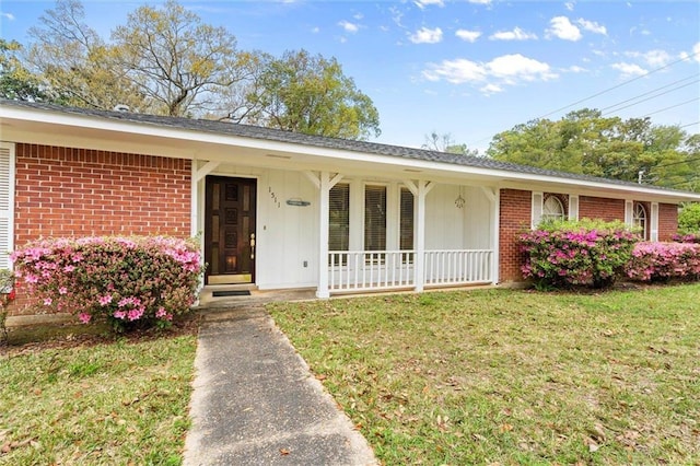 ranch-style home featuring board and batten siding, brick siding, a porch, and a front lawn