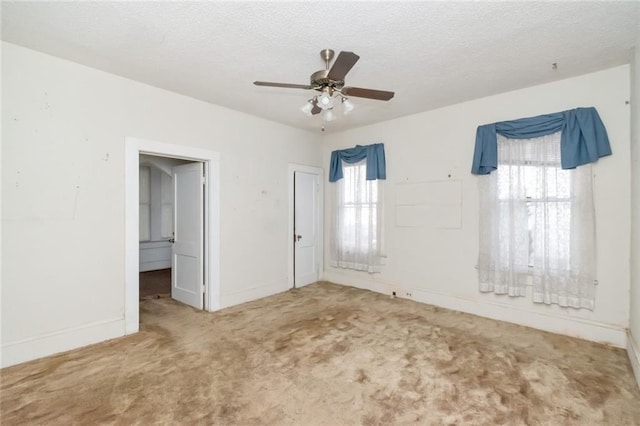 spare room featuring carpet flooring, ceiling fan, and a textured ceiling