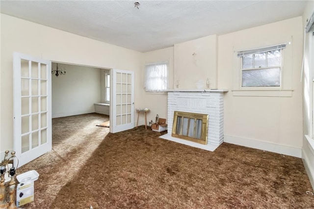 unfurnished living room with a brick fireplace, carpet flooring, and french doors