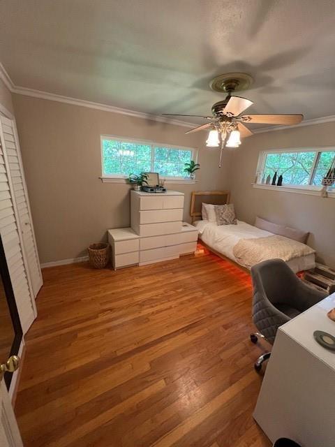 bedroom with crown molding, ceiling fan, baseboards, and light wood-style floors