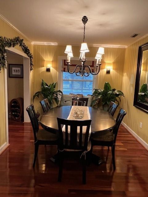 dining area featuring crown molding, visible vents, wood finished floors, and a chandelier