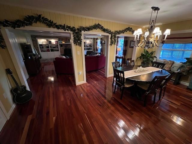dining area featuring ornamental molding, wood finished floors, and a notable chandelier