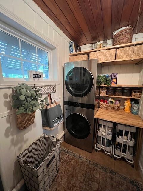 laundry area with laundry area, wood ceiling, and stacked washing maching and dryer