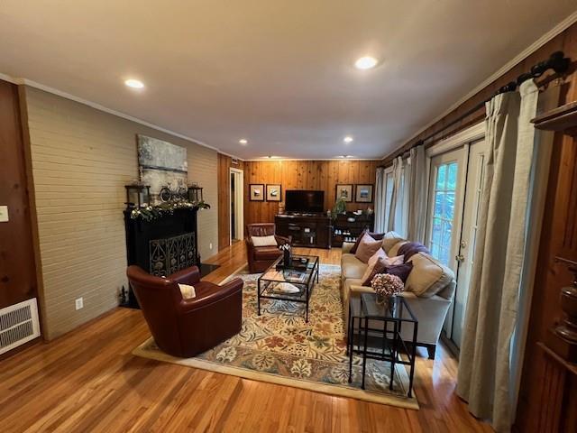 living room with visible vents, crown molding, wood finished floors, and a fireplace