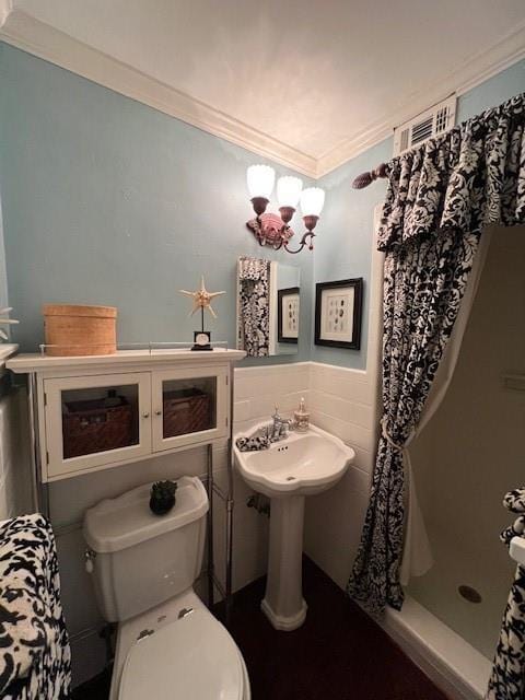 full bathroom featuring visible vents, ornamental molding, toilet, and a shower stall