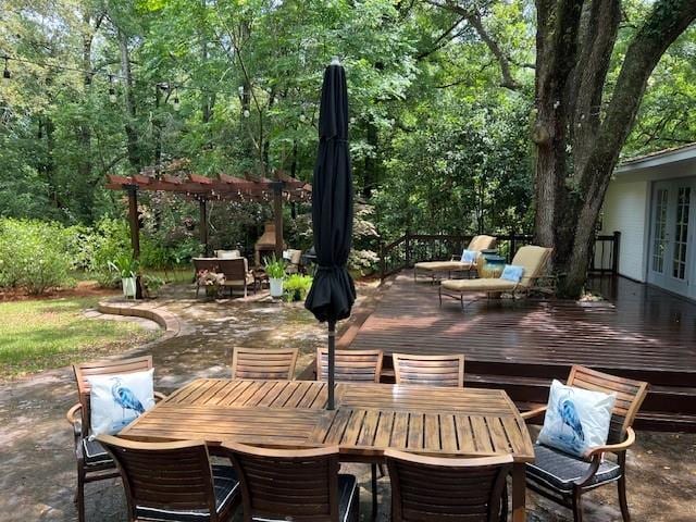 view of patio with a view of trees, french doors, outdoor dining area, and a wooden deck