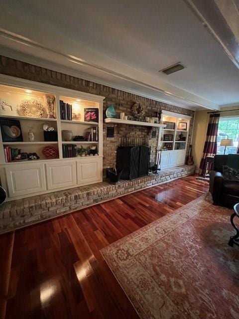 living room with built in features, a fireplace, wood finished floors, and visible vents
