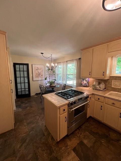 kitchen with stainless steel range, tile counters, a peninsula, and a wealth of natural light