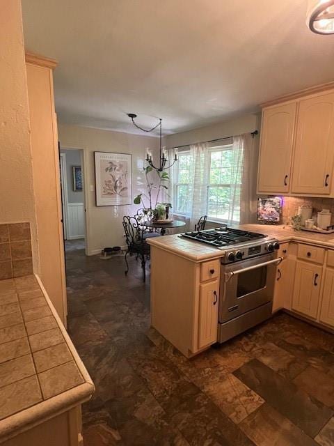 kitchen featuring high end stainless steel range, light brown cabinets, a peninsula, tile countertops, and decorative backsplash
