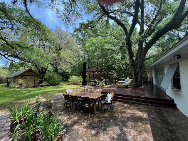 view of patio / terrace featuring outdoor dining area, an outbuilding, and a deck