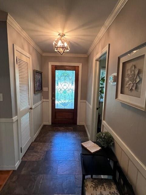 doorway to outside with crown molding, a chandelier, and a wainscoted wall