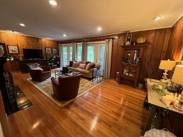 living room with crown molding, recessed lighting, wood finished floors, and wooden walls