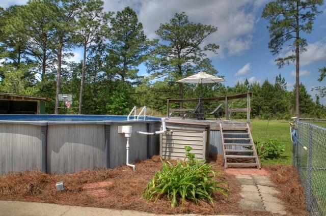 outdoor pool with fence, stairs, and a wooden deck