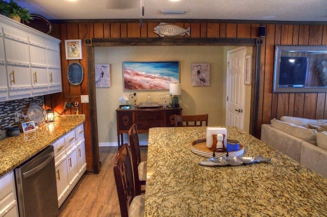 dining room with wood walls, visible vents, light wood-type flooring, and baseboards