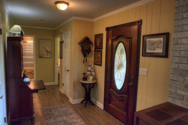 entryway featuring wood finished floors, ornamental molding, and baseboards
