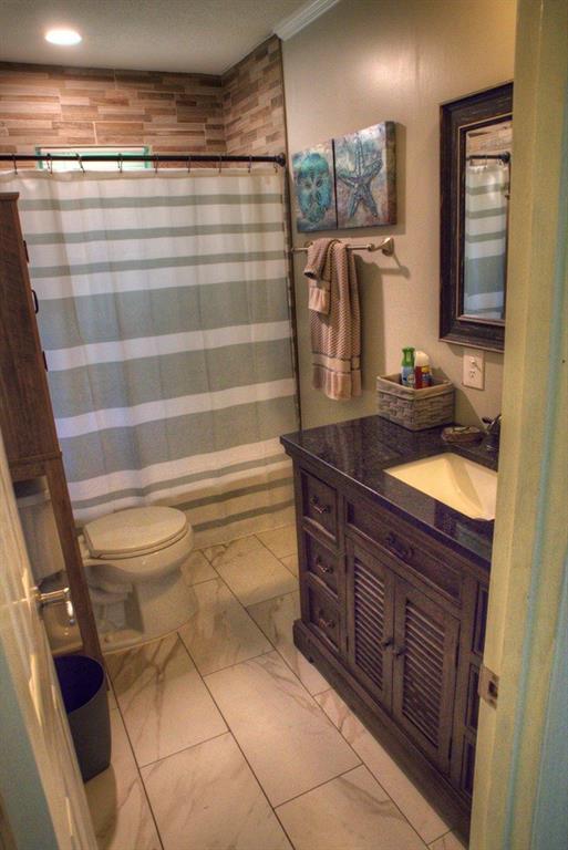 bathroom featuring a shower with shower curtain, toilet, ornamental molding, vanity, and marble finish floor