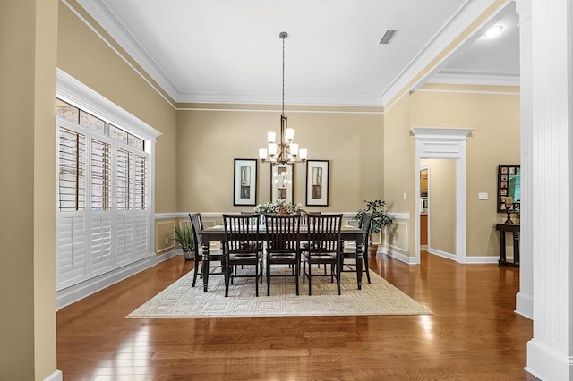 dining space featuring crown molding, an inviting chandelier, and hardwood / wood-style floors