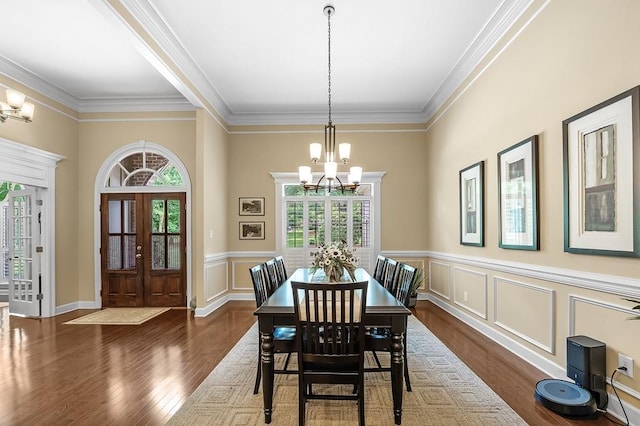 dining space with ornamental molding, a healthy amount of sunlight, dark wood-type flooring, and an inviting chandelier