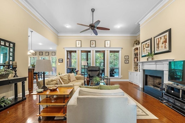 living room with dark wood-type flooring, ceiling fan, crown molding, and built in features