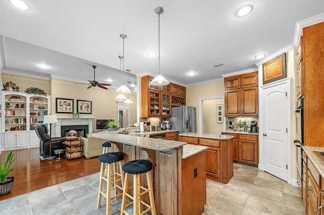 kitchen with crown molding, hanging light fixtures, a kitchen breakfast bar, kitchen peninsula, and stainless steel appliances