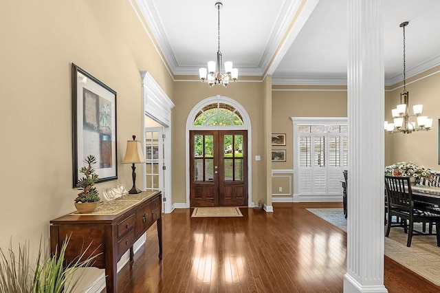 foyer entrance with ornamental molding, dark hardwood / wood-style floors, and a notable chandelier