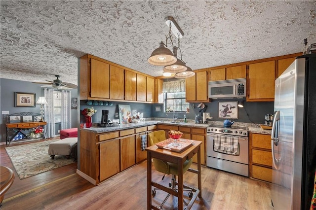 kitchen featuring pendant lighting, appliances with stainless steel finishes, sink, and light hardwood / wood-style floors