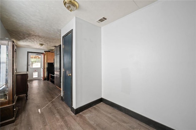 corridor with dark wood-type flooring and a textured ceiling