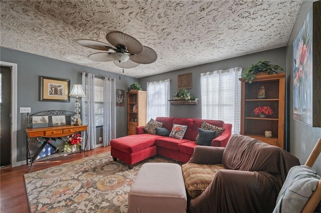 living room featuring hardwood / wood-style flooring, ceiling fan, and a textured ceiling