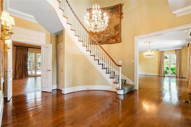 interior space with hardwood / wood-style flooring, a towering ceiling, crown molding, and a healthy amount of sunlight