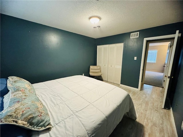 bedroom with a textured ceiling, light hardwood / wood-style flooring, and a closet