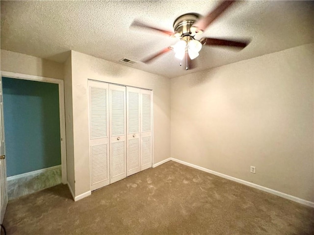 unfurnished bedroom featuring a closet, dark colored carpet, ceiling fan, and a textured ceiling