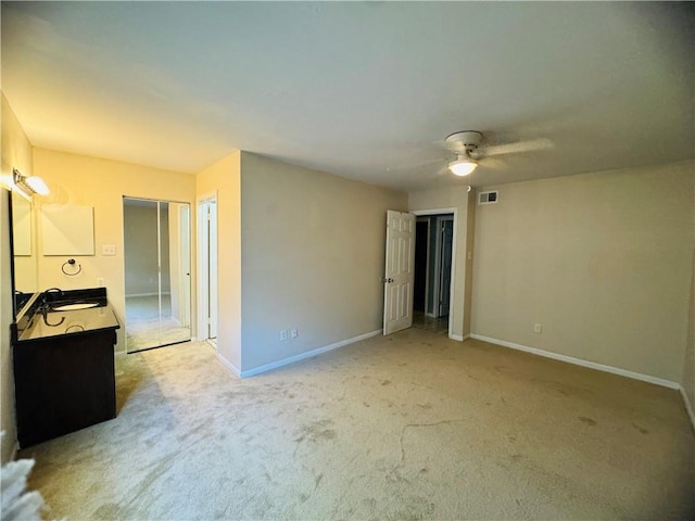 unfurnished bedroom featuring light carpet, sink, and ceiling fan