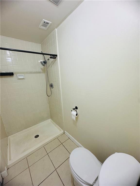 bathroom with a tile shower, tile patterned floors, and toilet