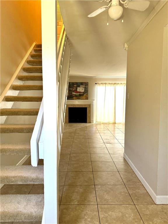 6701 Dickens Ferry Rd Unit 22, Mobile, AL 36608 - stairs with baseboards, tile patterned floors, ceiling fan, and a tile fireplace
